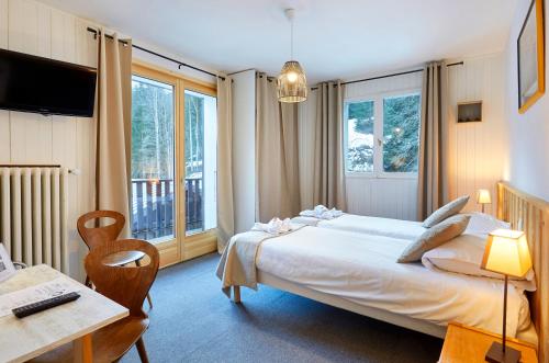 - une chambre avec un grand lit blanc, une table et des chaises dans l'établissement Hôtel Eliova l'Eau Vive, à Châtel