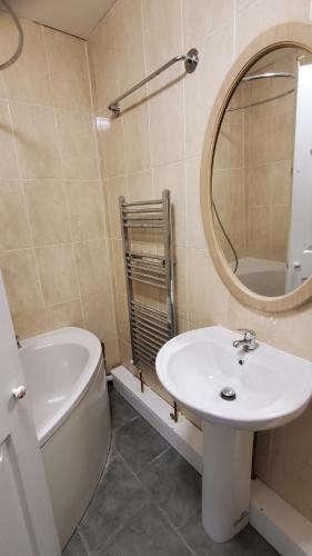 een badkamer met een wastafel, een toilet en een spiegel bij Cosy And Relaxing in Chatham