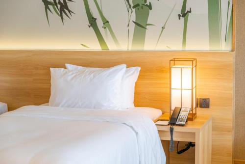 a bedroom with a bed and a lamp on a table at Da Nang - Mikazuki Japanese Resorts & Spa in Da Nang