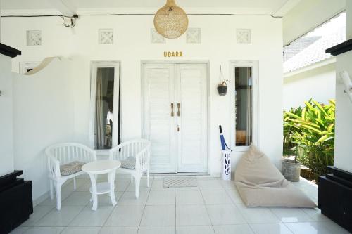 a white porch with a white table and chairs at Sukacita Hill in Uluwatu