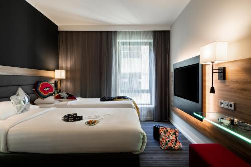 a hotel room with two beds and a flat screen tv at Moxy London Heathrow Airport in Hounslow