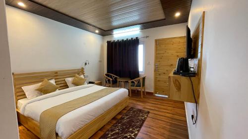 Habitación de hotel con cama y TV en The Deodar Stays en Kanatal