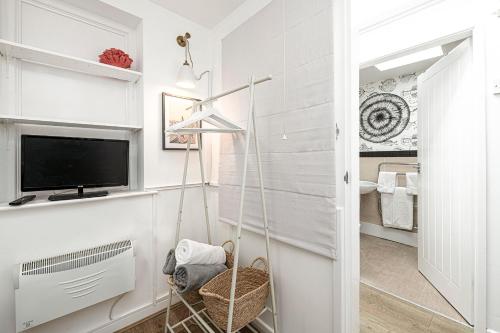 a white hallway with a tv and a room at Fisherman Cottage Llanfaes near Beaumaris in Llanfaes