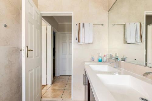 a white bathroom with two sinks and a mirror at Cape Town - Beautiful Modern Cottage in Cape Town