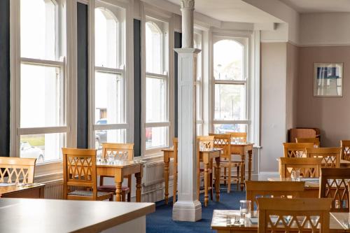 um restaurante com mesas, cadeiras e janelas em The County Hotel em Llandudno