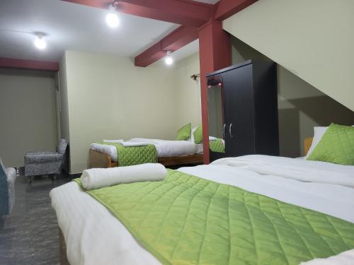 Habitación con 3 camas con sábanas verdes y blancas en Vati guesthouse en Shillong