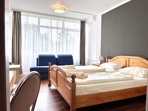 two beds in a room with blue chairs and a window at Landhotel Harz in Thale