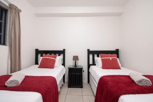 1 Schlafzimmer mit 2 Betten und roten Kissen in der Unterkunft 6 Bronze Bay Umhlanga Rocks in Durban