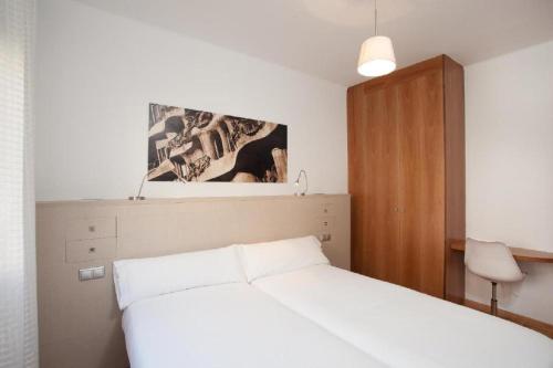 a bedroom with a white bed and a wooden cabinet at Ola Living Sagrada Familia in Barcelona