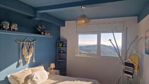 Dormitorio azul con cama y ventana en Villa Contenta Canyelles, en Canyelles