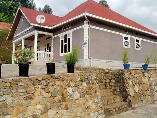 a house with a stone wall and potted plants at KIVU SUNSET GUEST HOUSE in Gitesi