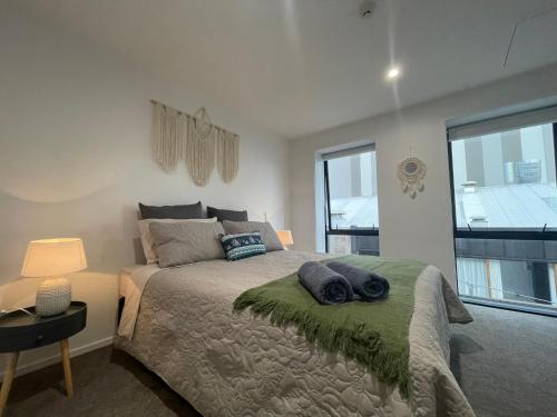 a bedroom with a bed and a large window at Luxury CBD 2 Bed Near Riverside Market Free Parking! in Christchurch