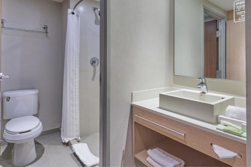 La salle de bains est pourvue d'un lavabo, de toilettes et d'un miroir. dans l'établissement City Express Suites by Marriott Playa del Carmen, à Playa del Carmen
