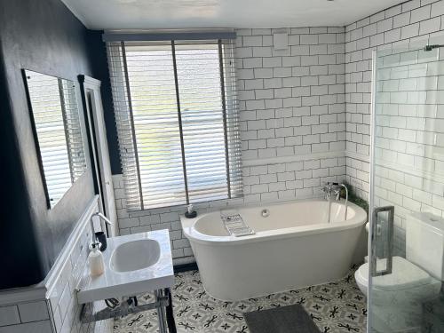 a white bathroom with a tub and a sink at London 2 Bedrooms with Private Garden Apartment Walking Distance to Underground Ideal for Families in London