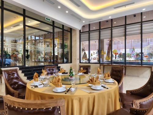 una sala da pranzo con tavolo, sedie e finestre di Hùng Vương Hotel a Móng Cái