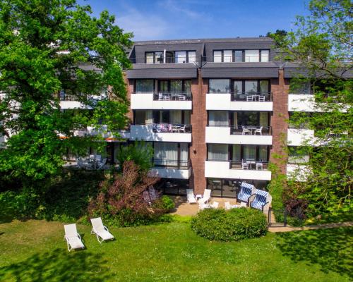 un edificio de apartamentos con un patio con sillas de césped en Appartement-Hotel Timmendorfer Strand, en Timmendorfer Strand