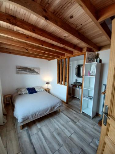 Schlafzimmer mit einem Bett und Holzboden in der Unterkunft Joli maisonnette in Bégaar