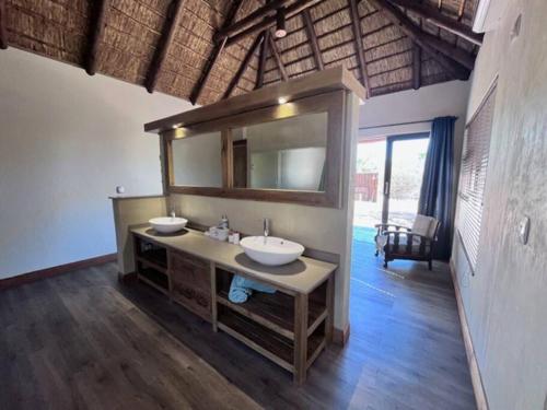 Bush Villa Ditholo 51 في Mmukubyane: حمام به مغسلتين ومرآة كبيرة