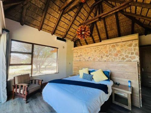 ein Schlafzimmer mit einem Bett und einem großen Fenster in der Unterkunft Bush Villa Ditholo 51 in Mmukubyane
