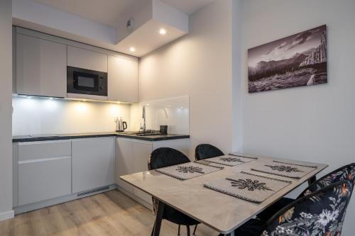a kitchen and dining room with a table and chairs at RentPlanet - Apartamenty Zakopiańskie in Zakopane