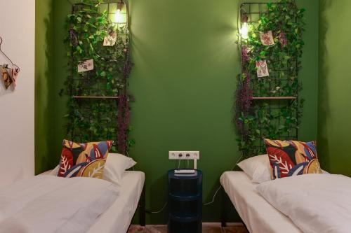 a room with two beds and a green wall with plants at ClinkMama in Amsterdam