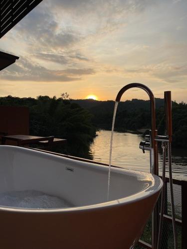 a bath tub sitting on a deck with a view of a river at Kwainoy Riverpark in Sai Yok