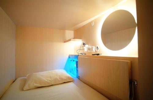 a small room with a bed and a mirror at Honeycomb Capsule Hostel Near Burjuman and Sharaf dg metro in Dubai