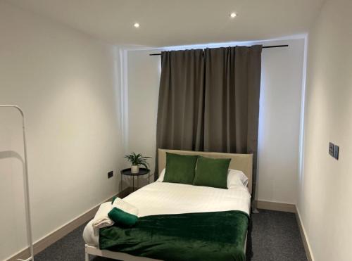 Dormitorio pequeño con cama con almohadas verdes en Captivating 2-Bed Apartment in Brentwood, en Brentwood