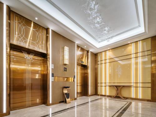 a lobby with gold walls and a elevator at Vienna International Hotel Xiamen Tong'an Industrial Concentration Area in Tong'an