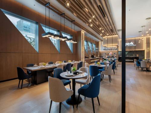 a restaurant with tables and chairs and a kitchen at Park Inn by Radisson Shanghai Shanghai Middle Jiasong Road Outlets in Qingpu