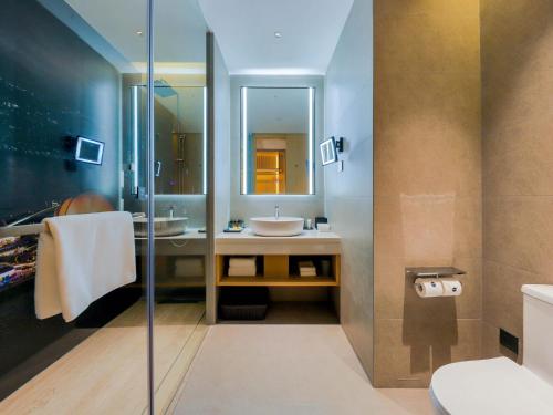 y baño con lavabo y ducha acristalada. en Park Inn by Radisson Zhuhai Gaolan Port en Nanshui