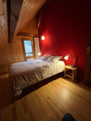 um quarto com uma cama com uma parede vermelha em Le Chal'heureux , grand chalet familial 8 personnes em Saint-Pierre-de-Chartreuse