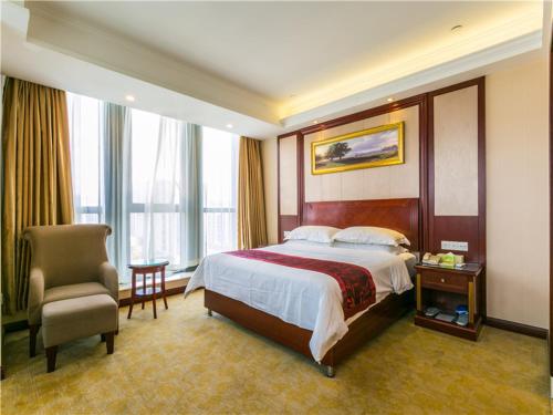 a hotel room with a bed and a chair at Vienna International Hotel Shanghai Hongqiao Airport Convention and Exhibition Center Huaxu Highway in Qingpu