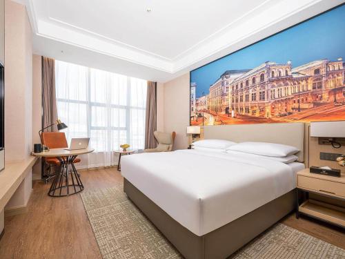 LongnanにあるVienna International Hotel Wudu Gujinli Longnanのベッド付きの客室で、壁には大きな絵画が飾られています。