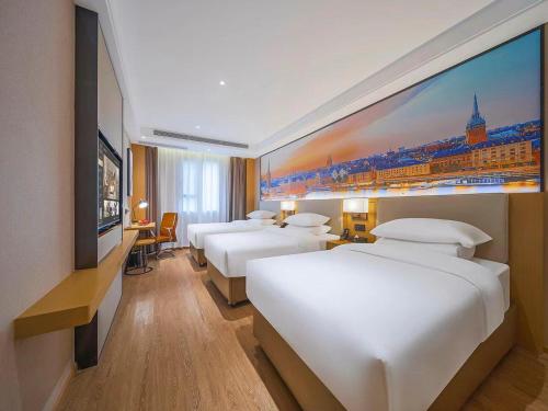 a hotel room with four beds and a large painting on the wall at Vienna International Hotel Kunming longquan road Finance University in Kunming