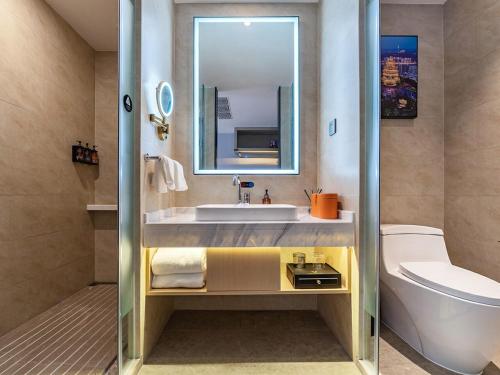 a bathroom with a sink and a toilet and a mirror at Vienna International Hotel Chongqing Jiangbeizui Financial Center in Chongqing