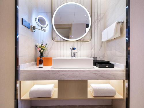 a bathroom with a sink and a mirror at Vienna International Hotel Lanzhou SASSEUR Outlets & Yellow Riverside in Lanzhou