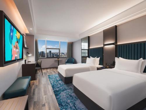 a hotel room with two beds and a flat screen tv at Park Inn by Radisson Hanzhong Central Square & High speed rail station in Hanzhong