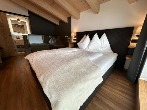 a bedroom with a large bed with white sheets at Pension Dorferwirt in Bramberg am Wildkogel