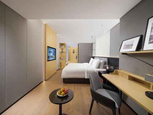 a hotel room with a bed and a bowl of fruit on a table at Park Inn by Radisson Chengdu FengHuang Mountain Sports Park in Xindu