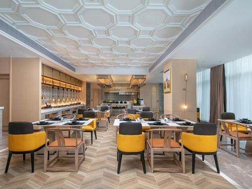 a restaurant with yellow chairs and tables and a bar at Vienna International Hotel Chengdu Shuangliu Airport Terminal Beijing Hualian in Chengdu