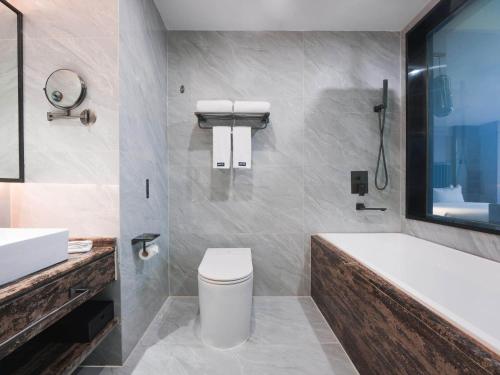 a bathroom with a tub and a toilet and a sink at Park Inn by Radisson Hanzhong Central Square & High speed rail station in Hanzhong