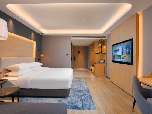 a bedroom with a large white bed and a television at Park Inn by Radission Tianjin Binhai International Airport in Tianjin