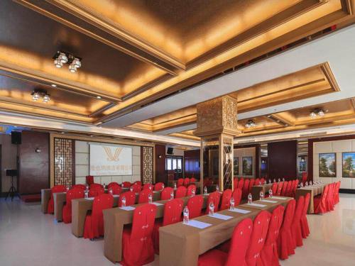 a conference room with red chairs and a screen at Vienna International Hotel FuJian PuTian Pearl in Putian