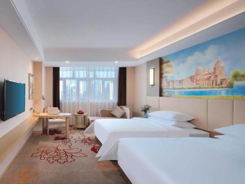 PutianにあるVienna International Hotel FuJian PuTian Pearlのベッドルーム1室(ベッド2台付)が備わります。壁には絵画が飾られています。