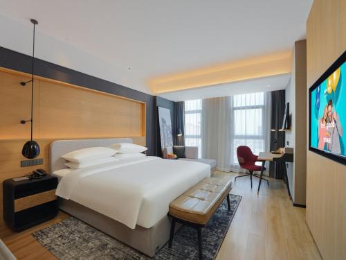 a hotel room with a large bed and a tv at Park Inn by Radisson Tianjin Jinghai Wanda Plaza in Jinghai