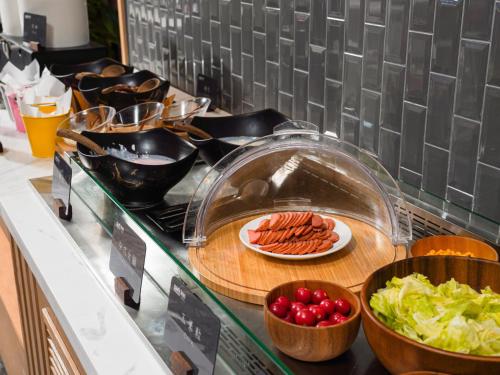 a counter top with plates of hot dogs and vegetables at Park Inn by Radisson Tianjin Five Old Street Nanjing Road in Tianjin
