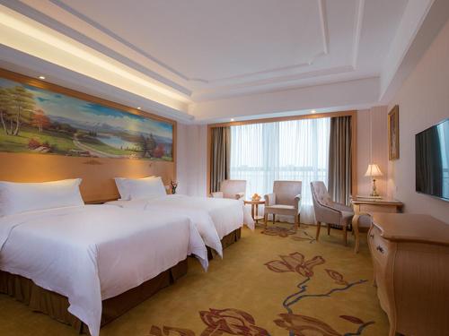 um quarto de hotel com duas camas e uma televisão em Vienna International Hotel Shenzhen Xiashuijing Metro Station em Shenzhen