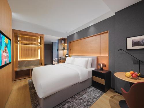 a large white bed in a room with a table at Park Inn by Radisson Tianjin Five Old Street Nanjing Road in Tianjin