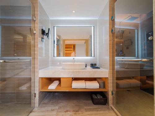 a bathroom with a sink and a mirror at Park Inn by Radisson Wenzhou Longwan International Airport Wanda Plaza in Xingqianjie